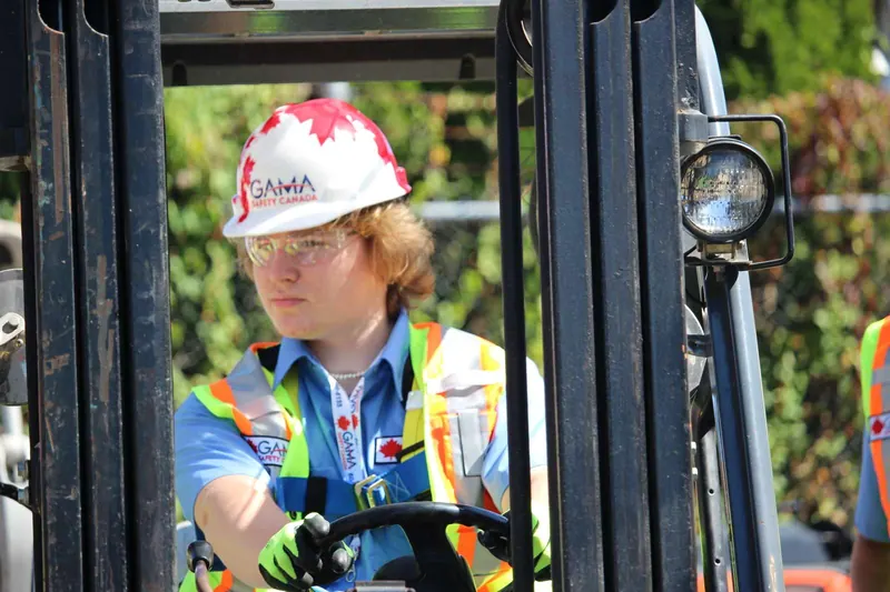Forklift trainee in a hard hat and safety glasses at the controls